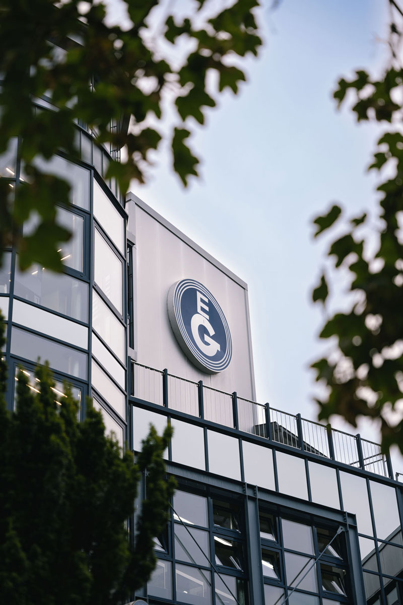 Detailaufnahme des Verwaltungsgebäudes am Standort Bonzelerhammer mit Fokus auf das Firmenlogo an der Fassade.